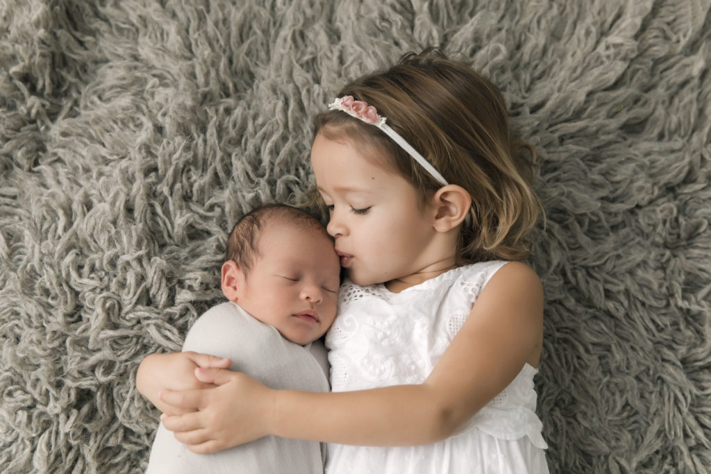 Big Sister kissing newborn baby brother