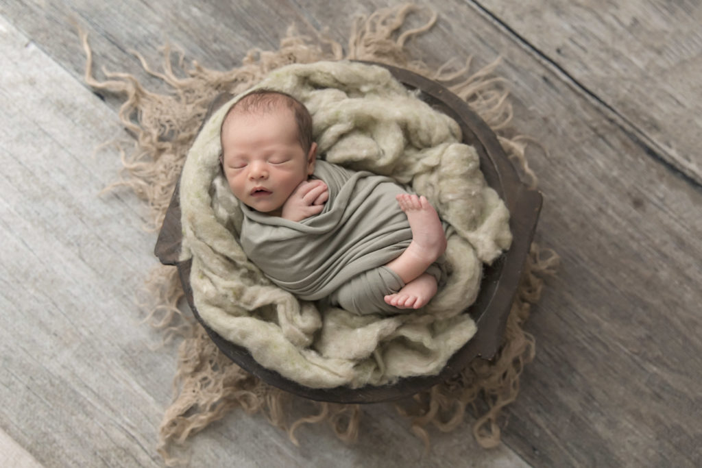  baby boy in green wrap in a bowl