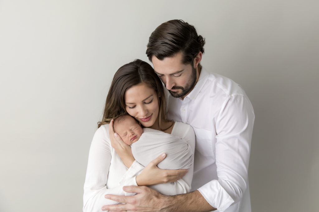 Mom and dad snuggling newborn baby boy