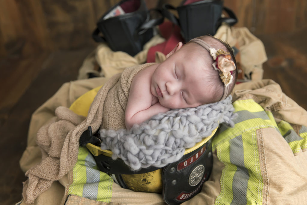 Newborn baby girl in daddy fire helmet 